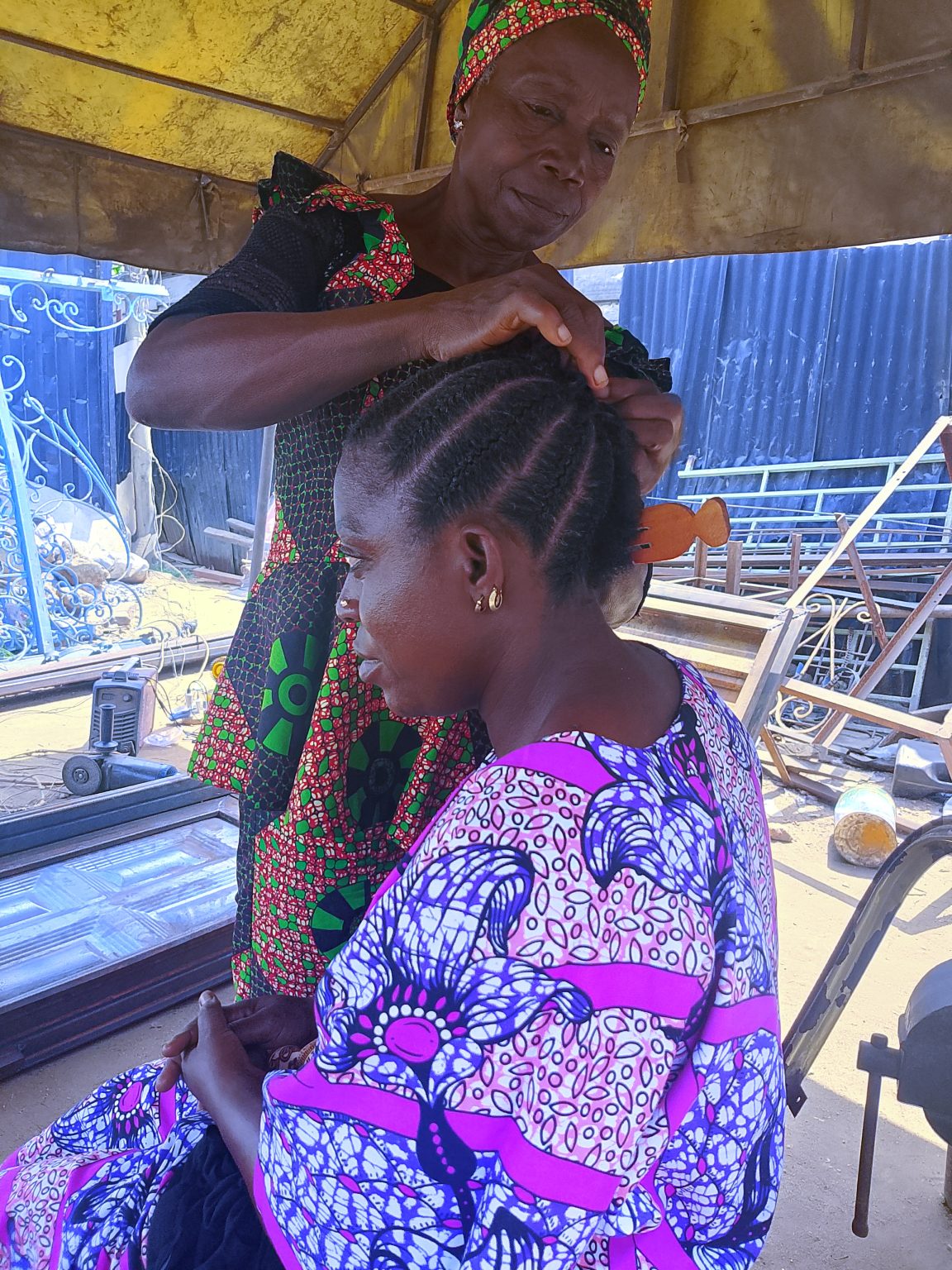African Setting

The older woman, dexterous 
Patiently the younger one sits
With a small wooden comb cornrows are created 
As the finished work glows
A beautiful maiden emerges