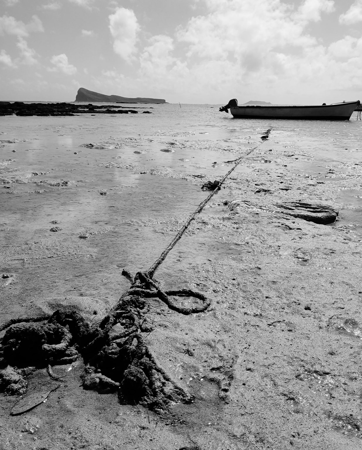 At Cap Malheureux, low tide reveals a knotted rope anchoring a small fishing boat, with Coin de Mire in the background. The scene reminds me of my family in the diaspora and how even the strongest tides cannot conceal our ties forever.