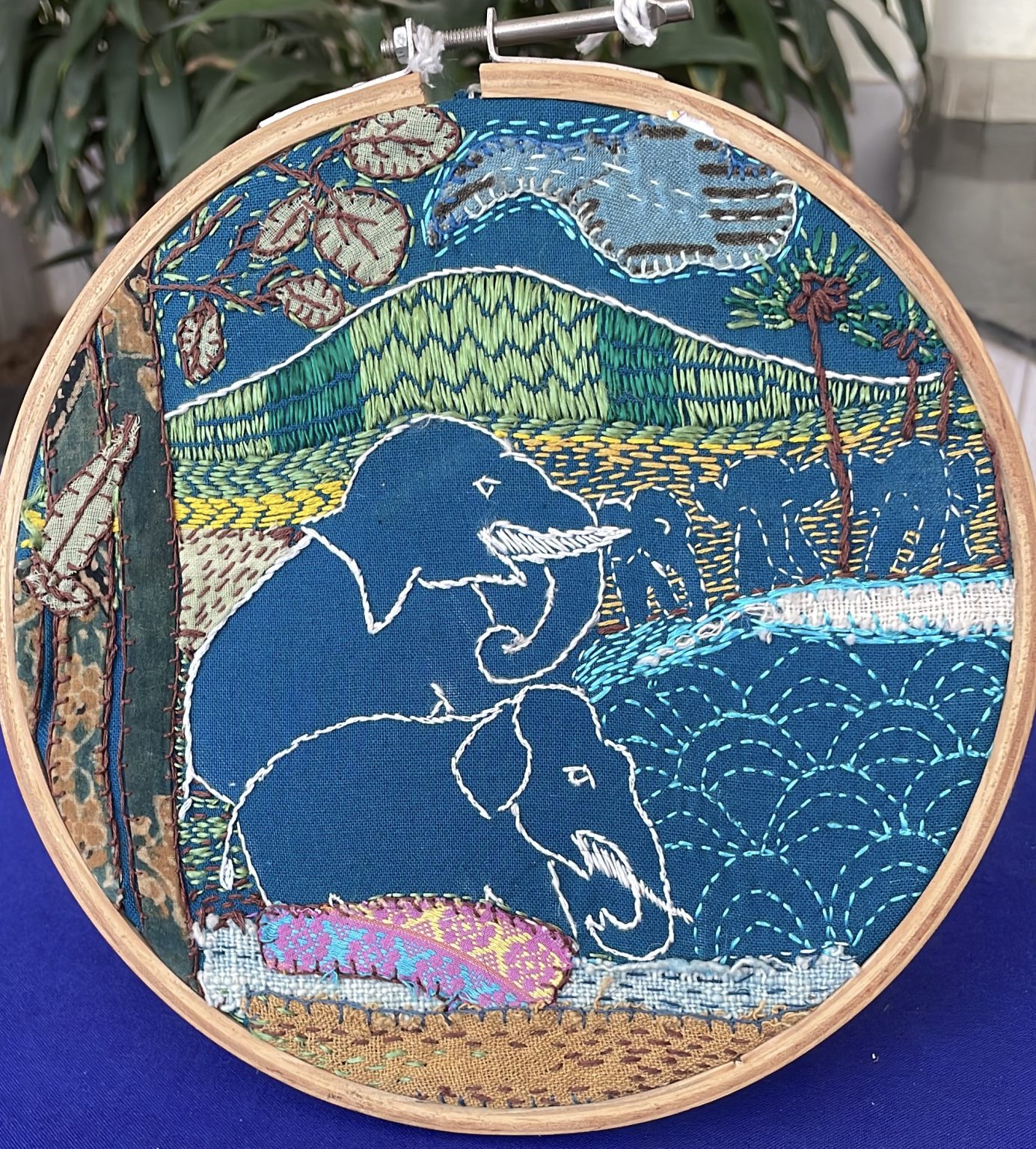 A 9-inch hoop brings together woven, embroidered, printed, and appliquéd natural and synthetic fabrics, using a range of thread techniques to reflect Prof. Macino and Raghunath Ji’s initiative of bringing the fertility of the land to the ecosystem of the forest.